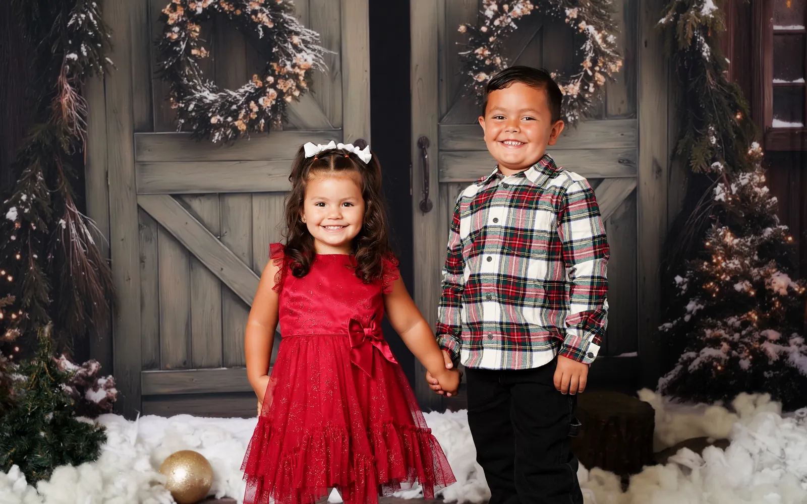A brother and sister holding hands in front of the Cozy Christmas Barn doors at LaLa Holiday HQ