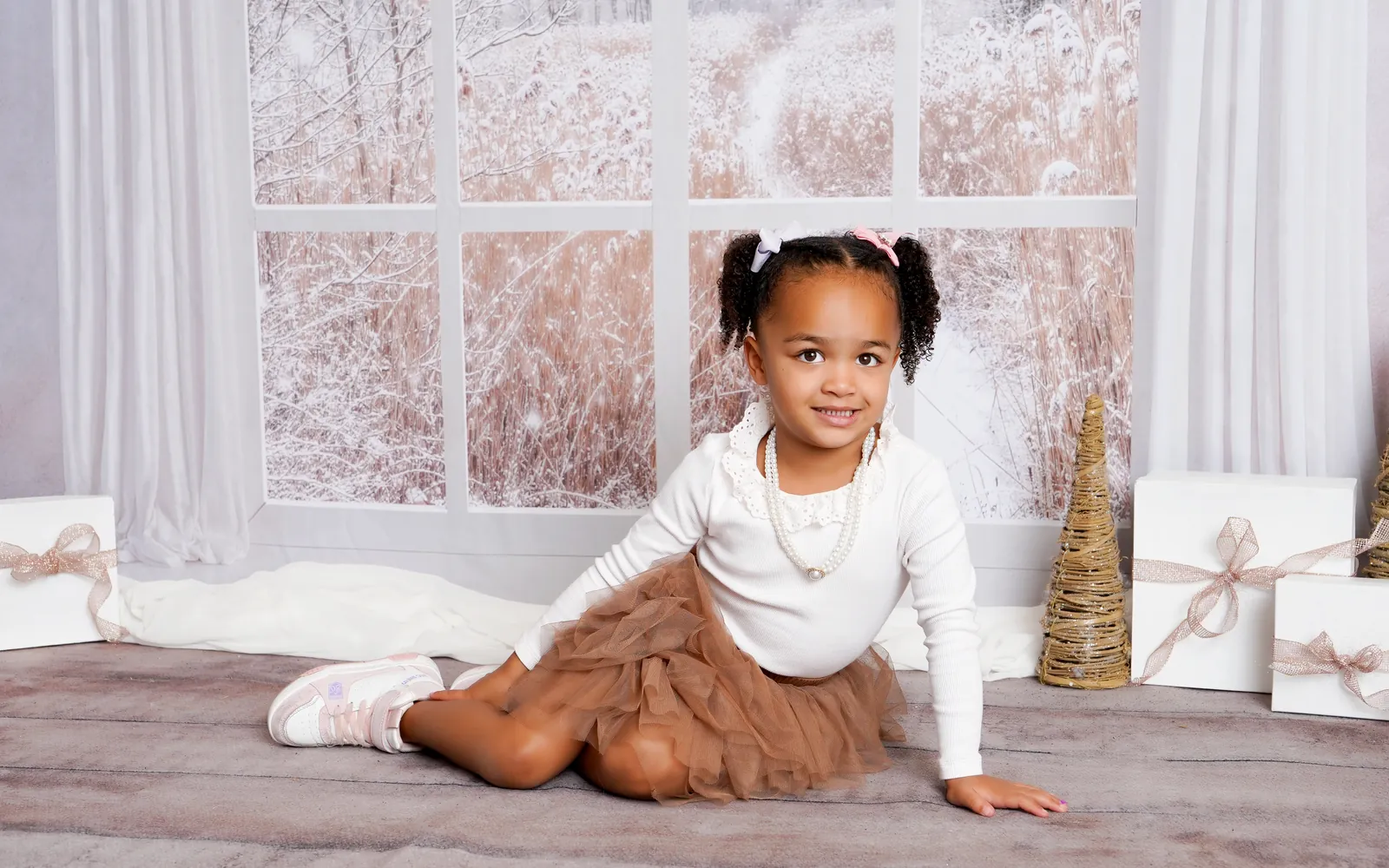 A girl in a tulle skirt sitting by the snowy Winter Window