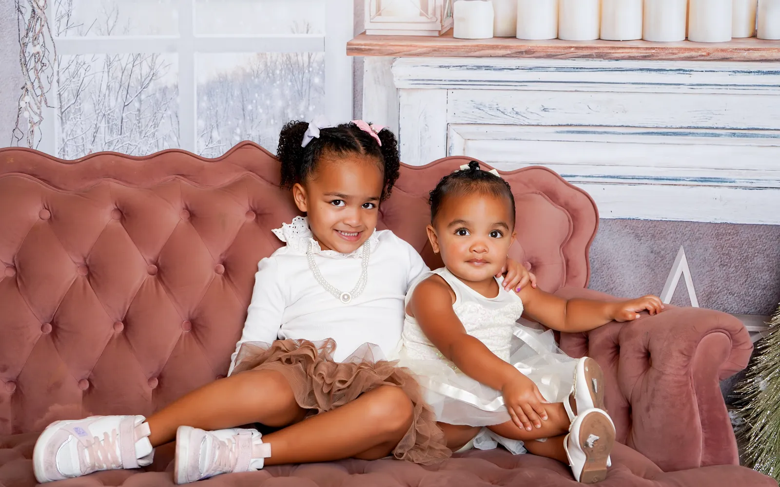 Two sisters in white and tulle on the pink settee of the Sugarplum Christmas set