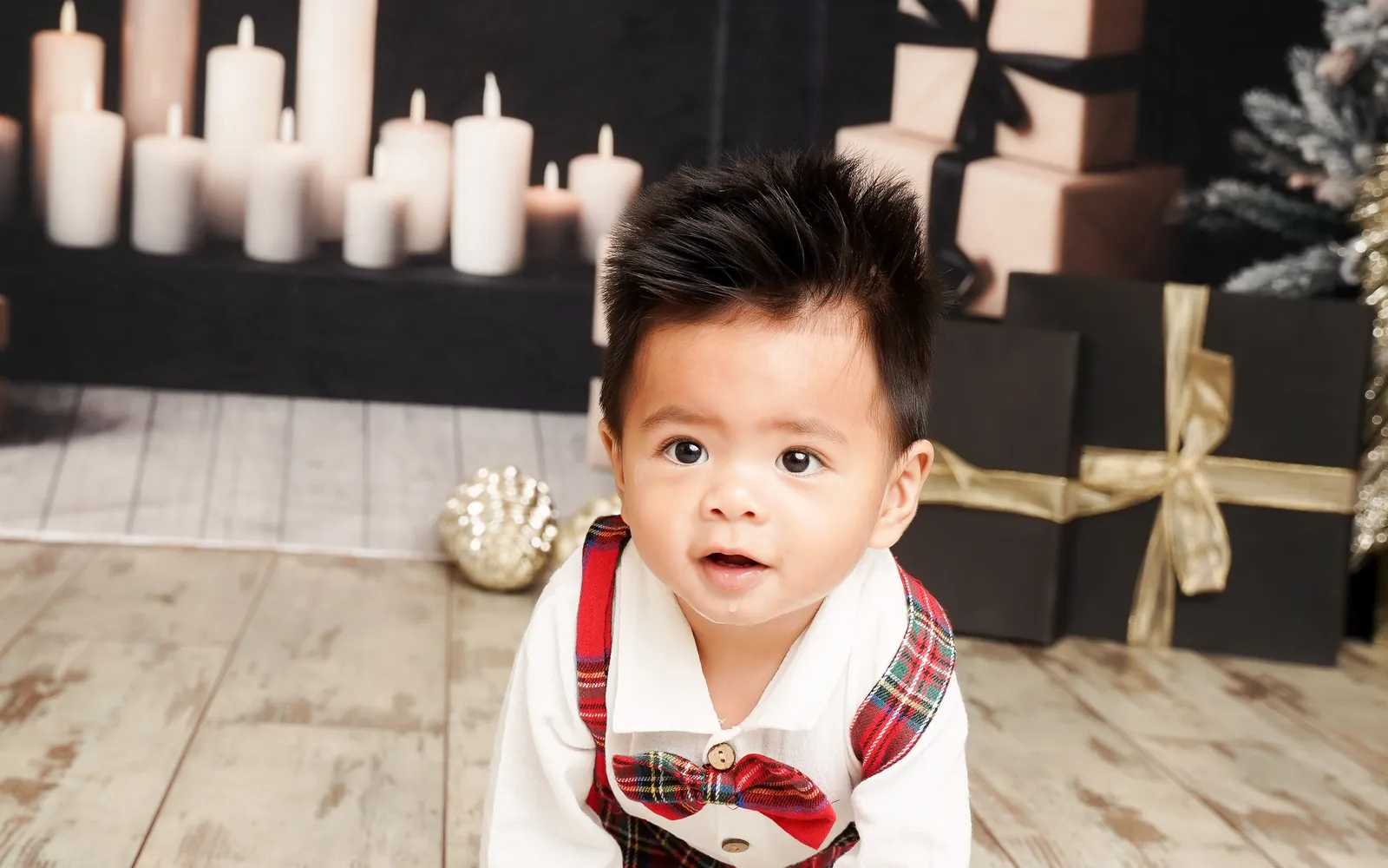 A baby in tartan crawling past the candles and presents on the Christmas Fireside set