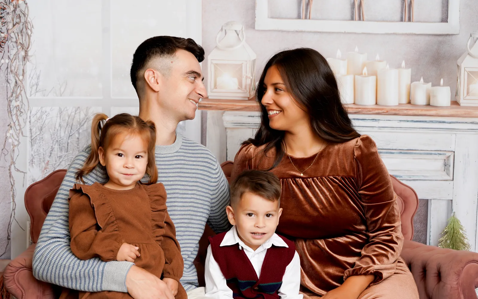 A mom and dad sharing a look with their two kids on the Sugarplum Christmas settee