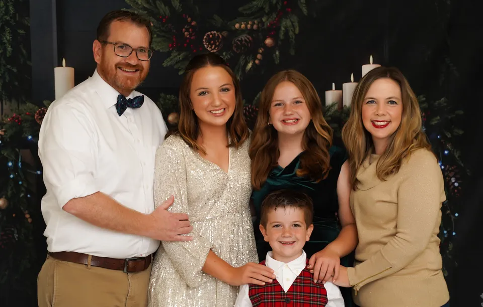 A family of five in front of the candlelit garland and wreath on the Christmas Fireside set